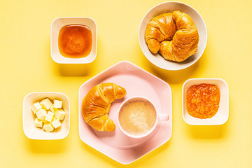 Naklejka na ściany i meble Coffee and croissants for breakfast on a yellow background