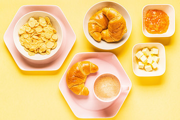 Coffee and croissants for breakfast on a yellow background