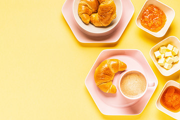 Coffee and croissants for breakfast on a yellow background