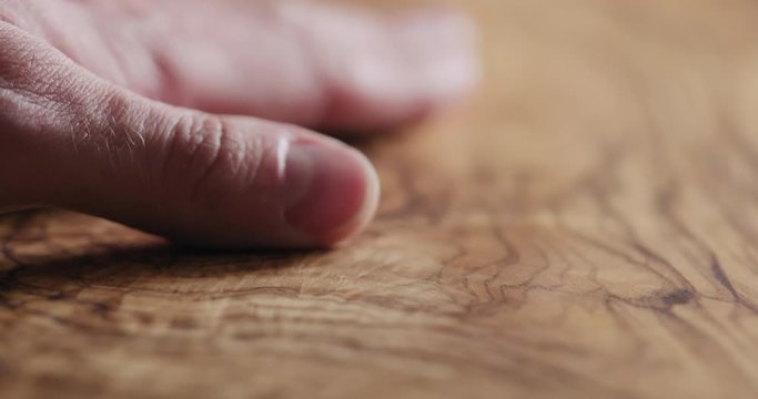 Slow motion man hand touch oil finished olive wood surface
