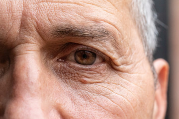 Old man face with wrinkles, grey haired pensioner ageing skin close up