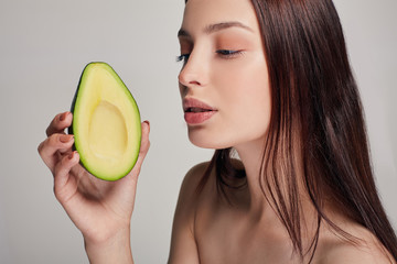 Profile side photo portrait of attractive tender brown-haired nude lady with perfect pure shine skin looking at avocado