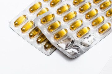 Omega 3 fish oil blister pack capsules, flax seed oil, vitamin D supplement, fatty acid supplement, three capsules missing on a white background, health care concept