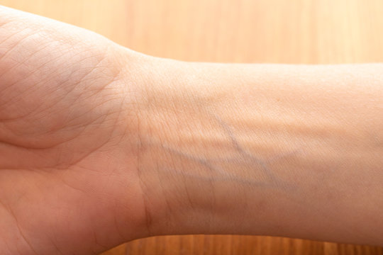 Human wrist with blue veins visible through skin close up