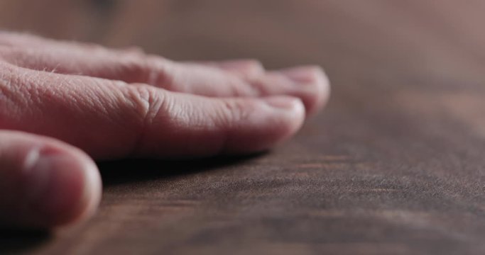 Slow motion man hand touch oil finished black walnut wood surface