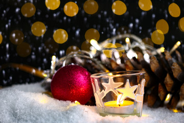 Fototapeta na wymiar christmas theme with candles, snow, .pinecone and christmas light with pokeh effect