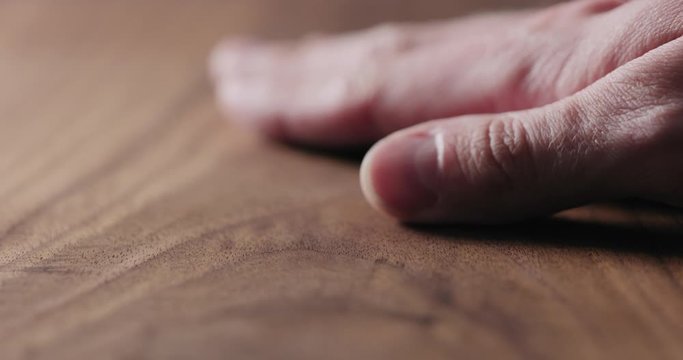 Slow motion man hand touch oil finished black walnut wood surface