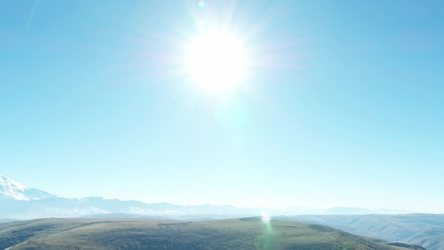 Mountain landscape, blue skt, road in the mountains, in the distance Elbrus, beautiful glare from the sun, from a height