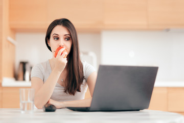 Woman Eating an Apple While Working on Laptop