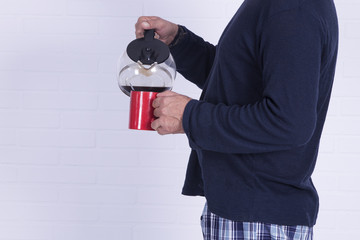 man with coffee cup and coffee maker on brick wall