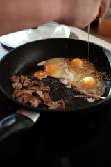 Hands preparing breakfast of fried eggs