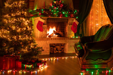 Christmas decorated tree in dark interior with fireplace, armchair, and window