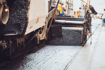 Laying asphalt with a construction machine on the street - road repair