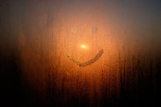 Drawed Smile On Condensated Window With Sunrise On Background