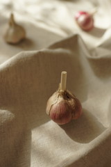 Three garlic bulbs on a vintage linen tablecloth. Healthy natural food