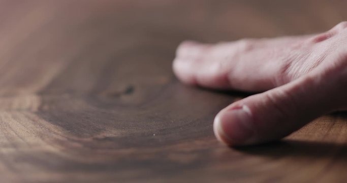 Slow motion man hand touch oil finished black walnut wood surface