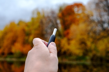 Heat-not-burn tobacco product technology. Modern heating system of tobacco in the hand of a man on...