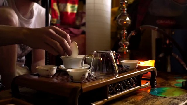 Pours Chinese tea into a teapot tea ceremony. Chinese instrument Board, Chachi, bowl, gaiwan.