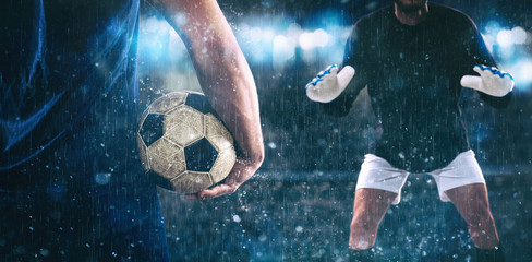 Soccer scene at night match with close up of a soccer striker holding the ball against the opposing...