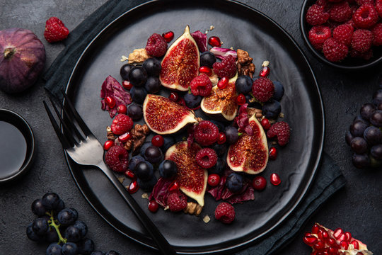 Fruit fig, grape, raspberry and pomegranate salad on black plate
