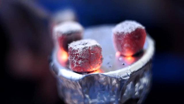 coconut coals on aluminum foil on hookah Cup close up selective focus. withers away on top of a bowl of sheesha