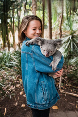 Magnetic island, Australia: Young happy woman holding koala and smiling