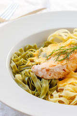 Lachsfilet auf grünen und hellen Bandnudeln