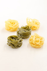 grüne und helle Nudelnester auf strukturiertem, weißem Hintergrund