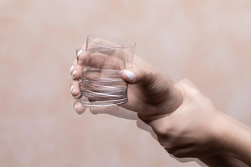 Trembling hand holding glass with alcohol drink - obrazy, fototapety, plakaty