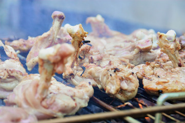 Close up raw chicken on the grill with smoke.