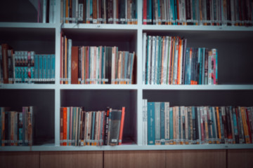 Blurred of Books in public library with bookshelves. Stack piles of literature text for reading...