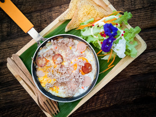 eggs pan with topping on wooden background for breakfast menu.