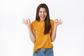 Excited, cheerful lucky girl believe everything be okay, close eyes scream delighted and thrilled, showing ok, perfection or approval sign, smiling anticipating awesome party, white background