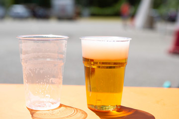 Beer with foam in plastic disposable glasses