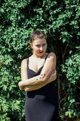 Young beautiful girl in black dress with tattoo on her hand in the park 