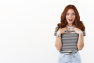 Surprised cute feminine redhead woman in striped t-shirt look with awe and amazement, gasping press palms to chest ambushed, receive cute gift, standing thankful, appreciate efforts
