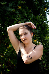 Young beautiful girl in black dress with tattoo on her hand in the park 