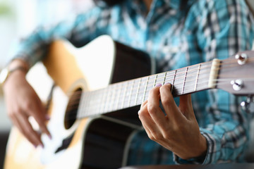 Fototapeta premium Focus on female hand playing bracket in music workshop. Professional guitar player having musical lesson for students. Art concept. Blurred background