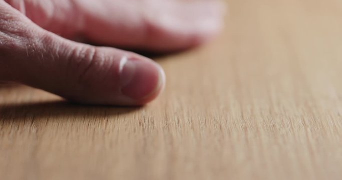 Slow motion man hand touch oil finished oak wood surface