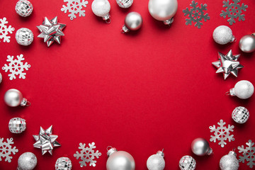 Christmas and New Year holiday background. Xmas greeting card. Christmas silver ornaments on red background top view.	