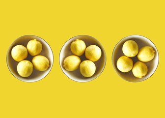 Lemons in bowls, bright yellow background 
