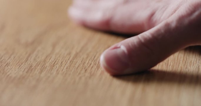 Slow motion man hand touch oil finished oak wood surface