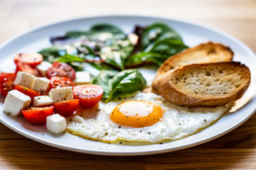 Breakfast - fried egg, toasts and vegetable salad