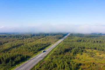 Beautiful hight way road high angle beautiful view of the fog over the road on an early summer morning in central Russia. Bird's eye view of the road and skyline.