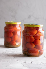 Pickled tomatoes in glass jars, closeup. With dill and garlic