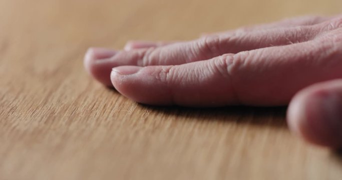 Slow motion man hand touch oil finished oak wood surface