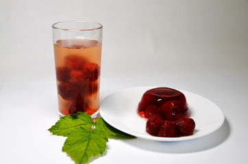 On a white background dessert - a glass of compote and strawberry jelly.
