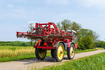 Agricultural machine, seen from behind, driving on a country road in Groningen, the Netherlands, Europe.