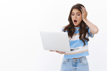 Concerned troubled brunette female gasping shocked, hold laptop grab head stare computer display...