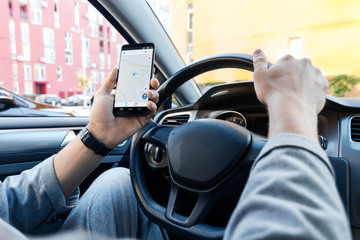 Closeup male hand is holding smartphone with online map on screen, shows way to home. Man  driver...